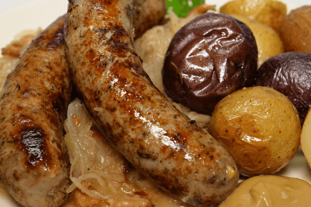 close up of beer braised sausages with roast baby potatoes and sauerkraut.