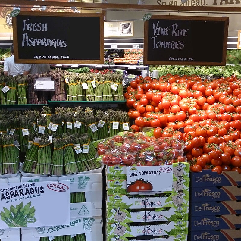 Fresh display of Asparagus and Tomatoes inside Farm Boy Wellington, London.