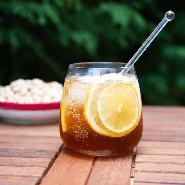 Glass of juice garnished with lemon wheels on wooden table