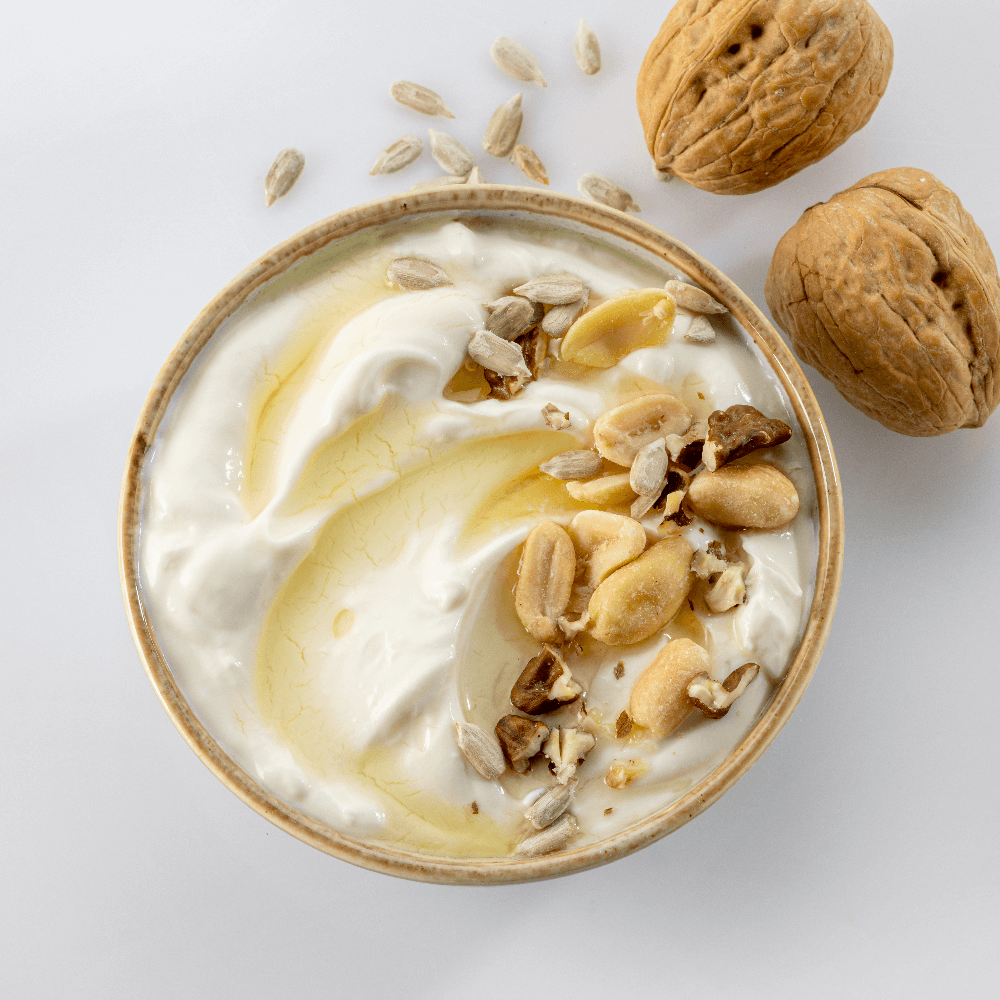 Overhead shot of plain yogurt dressed with honey and chopped nuts.