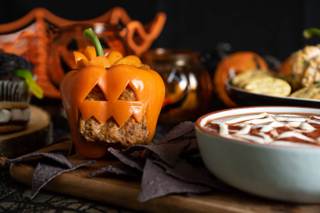 Orange bell pepper cut into jack-o'-lantern shape with bean dip inside.
