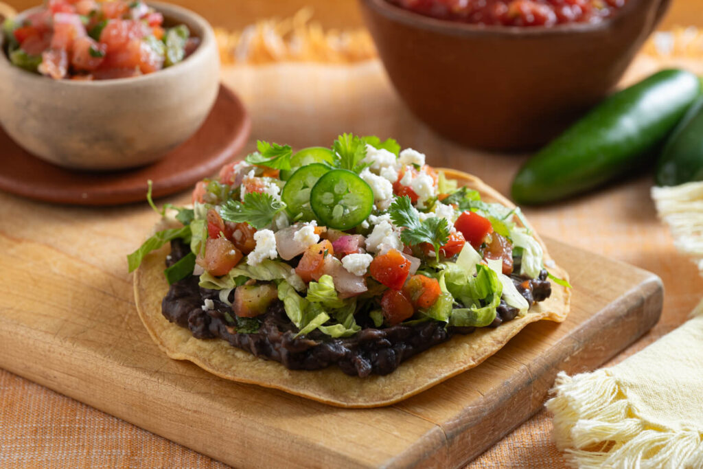 Yellow corn tortilla black bean tostada with cheese, cilantro, and pico de gallo