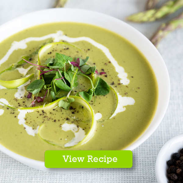 A bowl with creamy asparagus soup garnished with microgreens and fresh cream
