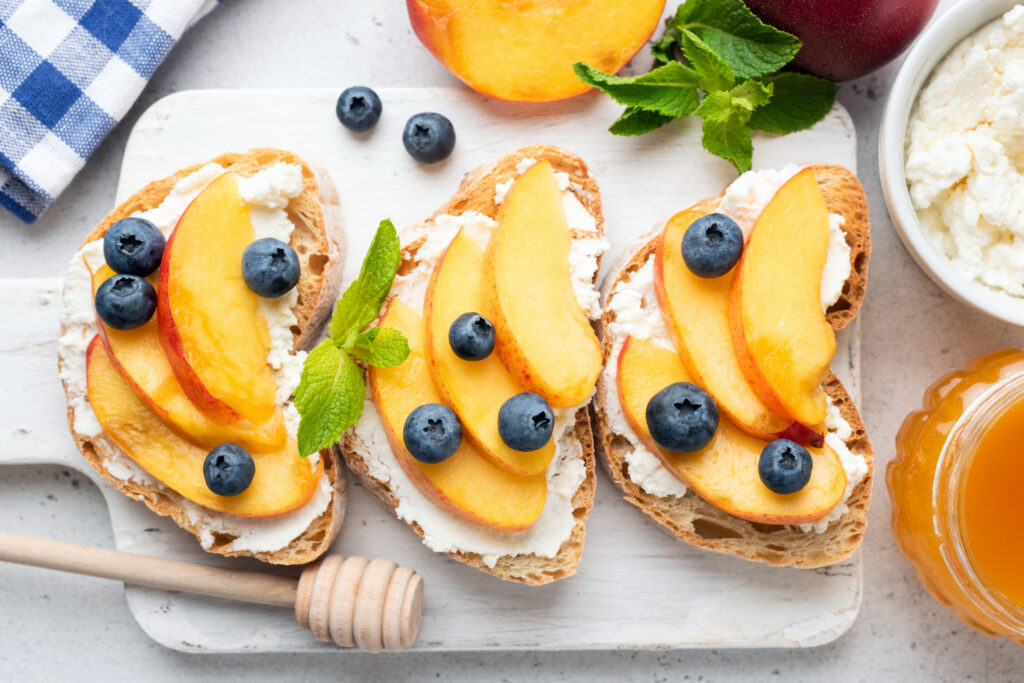 Toast with Ricotta Cheese, Honey, Peaches, and Blueberries.