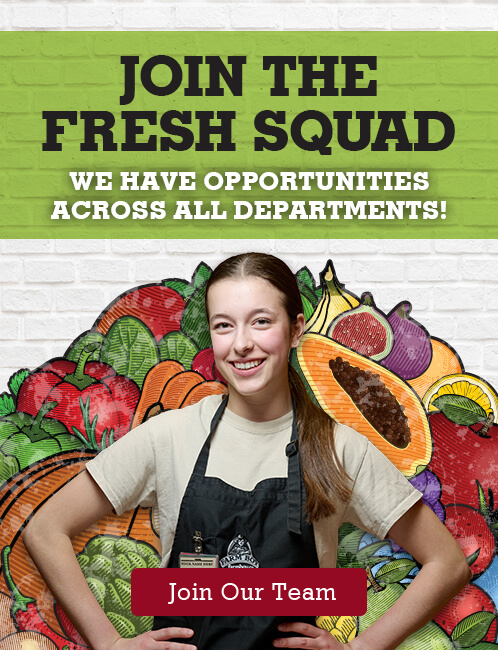 A recruitment poster featuring a young woman wearing a farm Boy work apron and smiling, standing in front of a colourful illustrated background of various fruits and vegetables. The poster reads, "JOIN THE FRESH SQUAD" at the top, followed by "WE HAVE OPPORTUNITIES ACROSS ALL DEPARTMENTS!" Below the woman, there is a red button that says "Join Our Team."