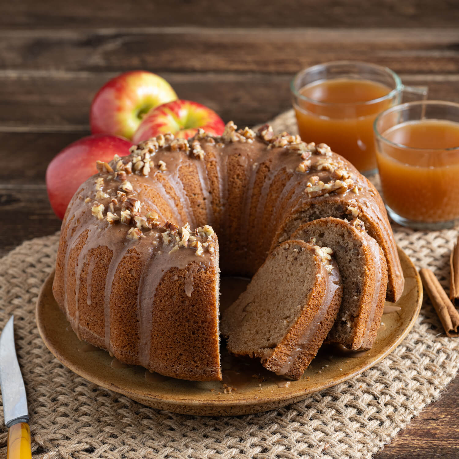 Plate with an Apple Cider Bundt Cake with a glaze and garnished with toasted nuts