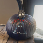 Completed design on a pumpkin. It's all black with an outline of a ghost and skull on top of the pumpkin.
