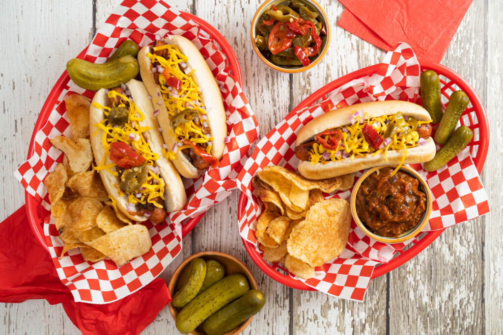 two red plastic baskets filled with chili dogs, potato chips, and pickles.