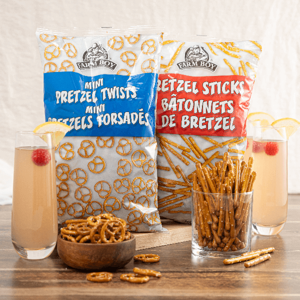 Two bags of Farm Boy Pretzels behind two glass containers filled with them.
