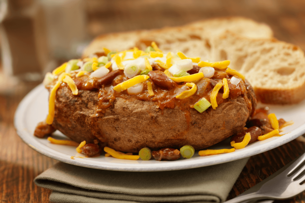 "Baked Potato Topped with Chili, Sour Cream, Green Onions and Cheddar Cheese with Garlic Bread