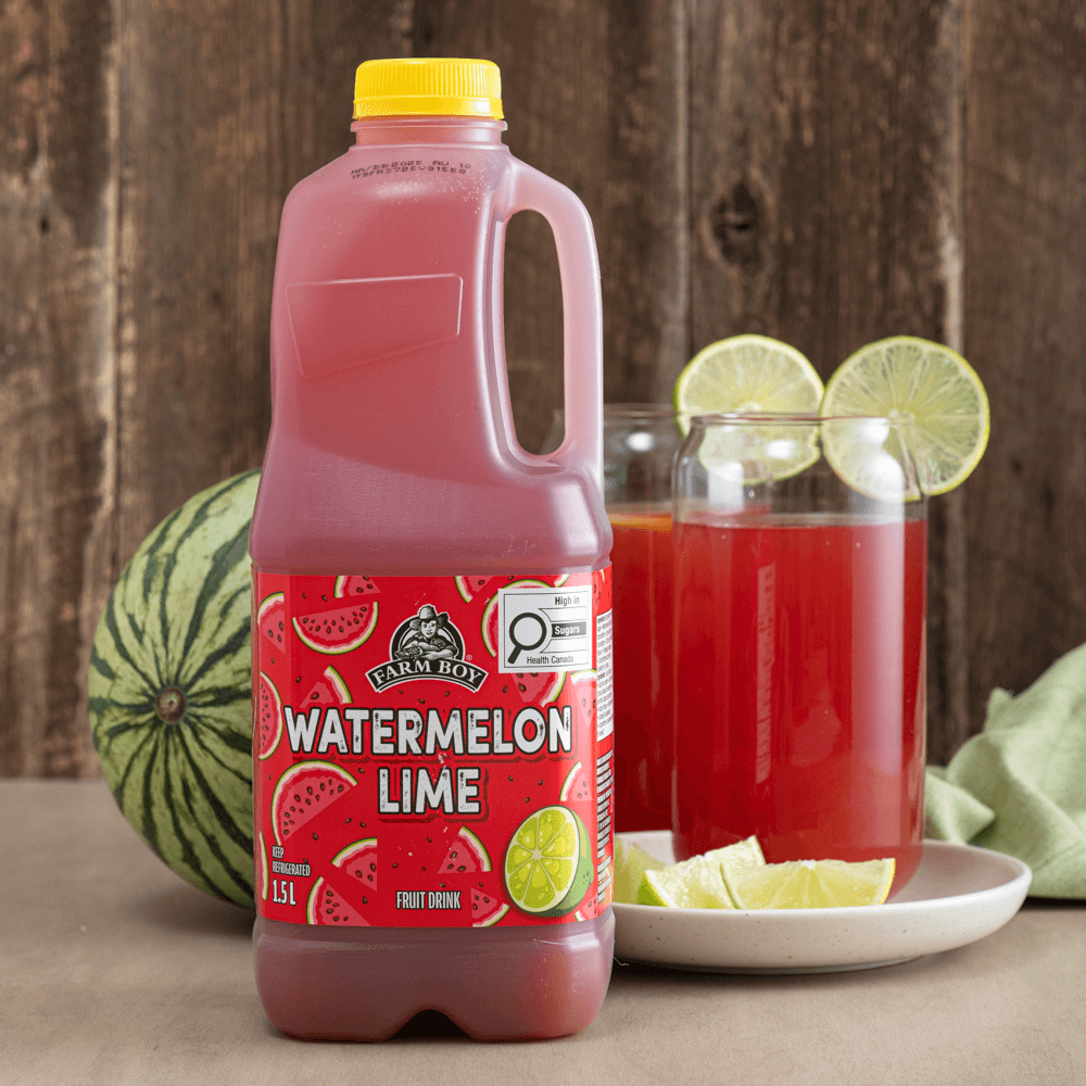 Jug of Farm Boy Watermelon Lime Fruit Drink with two glasses of red juice garnished with wheels of lime