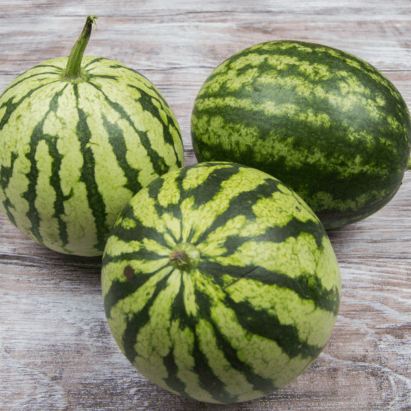 Three mini watermelons on wooden table