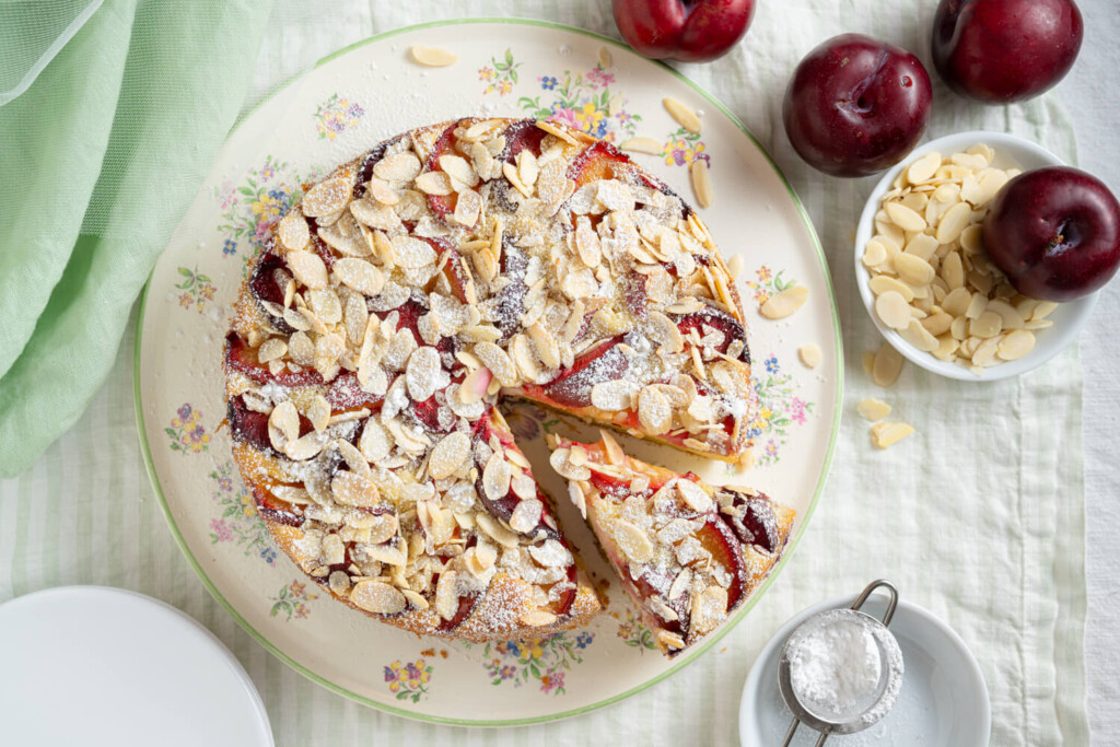 Overhead image of almond plum cake with slice removed
