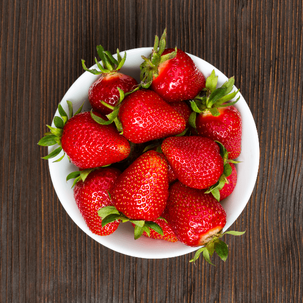Overhead image of bowl of strawberries on wooden table