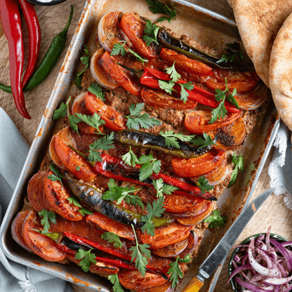 Tray of lamb kebab with onion, herbs, and tomatoes