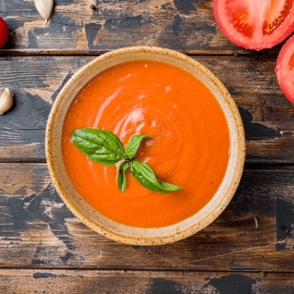 Overhead image of bowl of tomato soup on wooden table