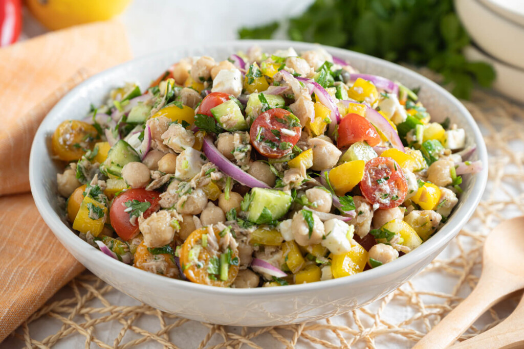 White serving dish with a salad of chickpeas, cucumbers, tomatoes, bell peppers, and tuna