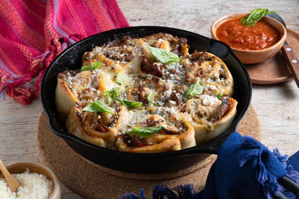 Cast iron pan with homemade pizza rolls for an easy lunch topped with cheese and fresh basil