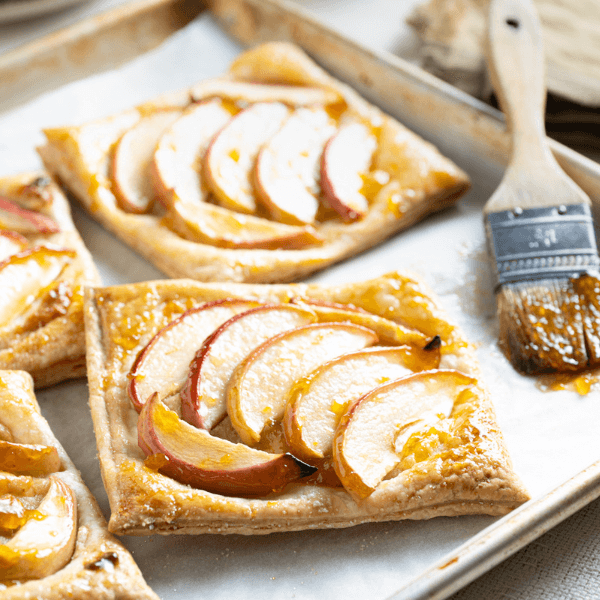 Baking tray with apple frangipane tarts and pastry brush