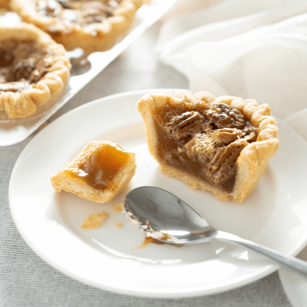 White plate with gooey maple butter tart with pecans and spoon