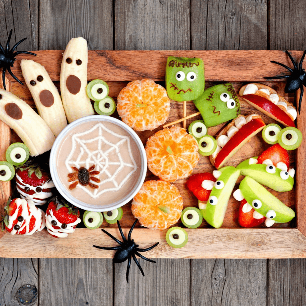 Top view of Halloween fruit platter with apples, bananas, kiwi, oranges, and strawberries