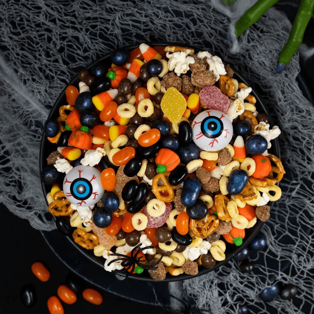 Top view of bowl of Halloween snack mix with popcorn, pretzels, and candy
