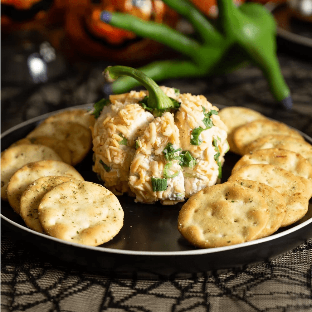 Cheese ball shaped like a pumpkin surrounded by crackers on a plate