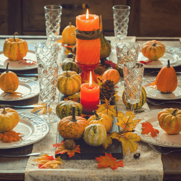 Autumn table setting for Thanksgiving dinner with candles, pumpkins and leafs