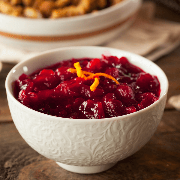 White bowl with cranberry sauce garnished with orange peel