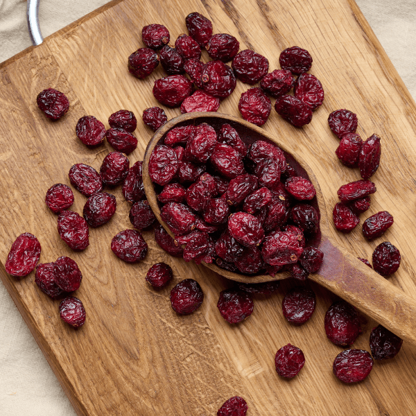 bunch of dried cranberries in a wooden spoon on a brown table. Delicious berry, top view