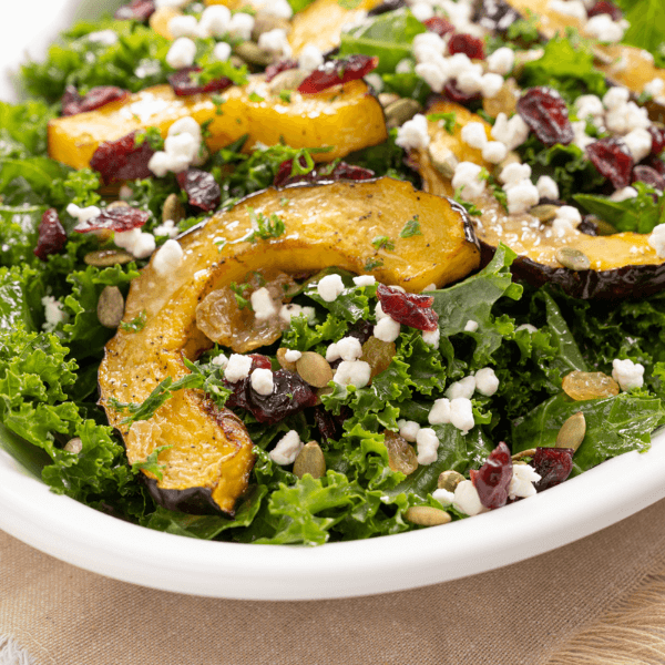 Serving dish with Roasted Butternut Squash Salad with goat cheese crumbles, dried cranberries, and raisins