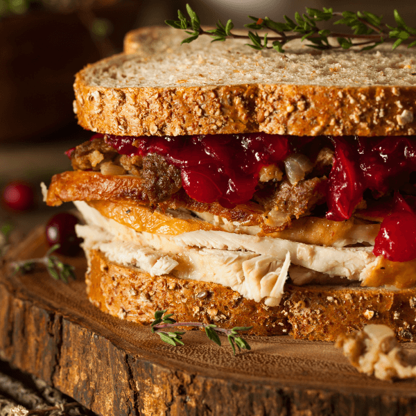 Sandwich made from holiday leftovers with turkey, cranberry sauce, and stuffing on multigrain bread