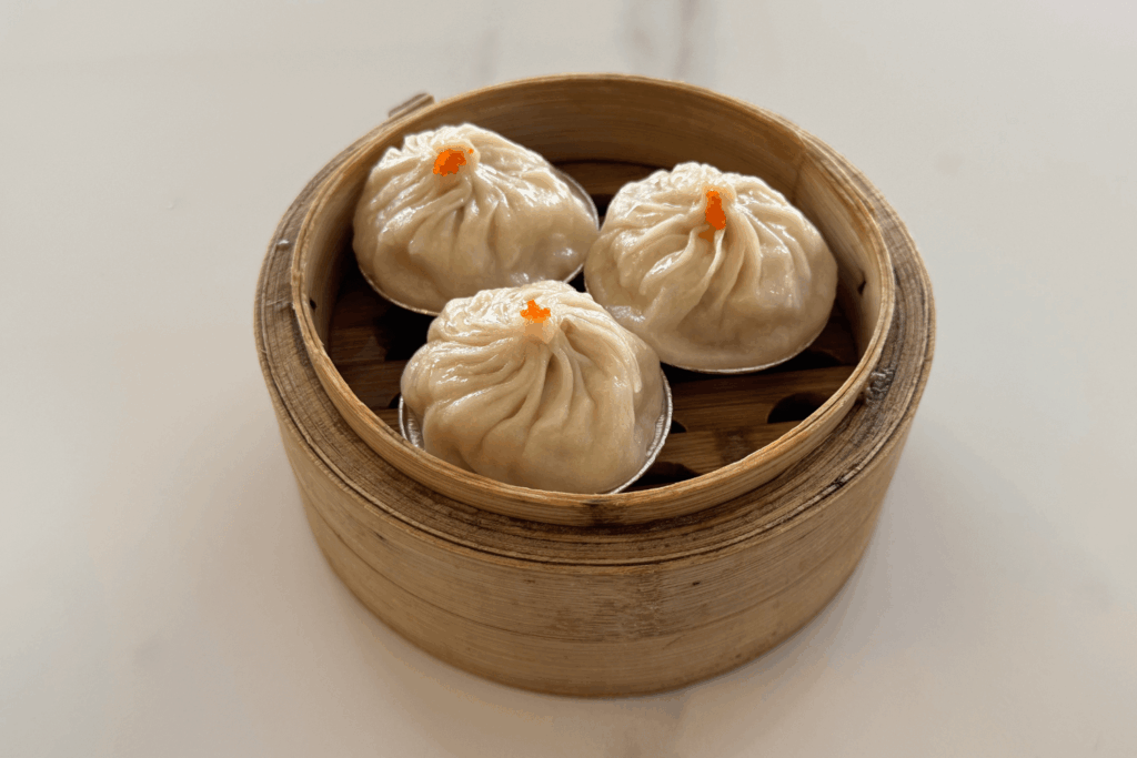 steamed soup dumpling in black bowl with spicy chili mala sauce on white table