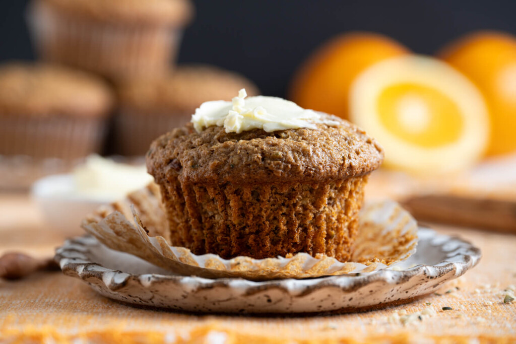 Close up of carrot pecan bran muffin with a smear of butter on top