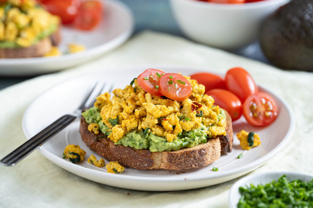 Close up of plate with fork with slice of toast topped with tofu scramble and fresh tomatoes as a healthy recipe for brunch or breakfast