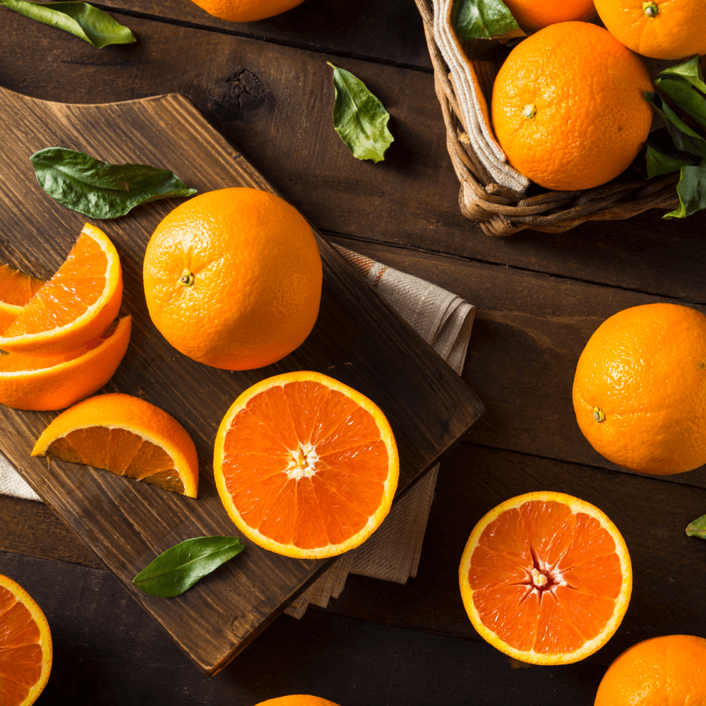 Sliced and whole Cara Cara oranges on dark wooden background