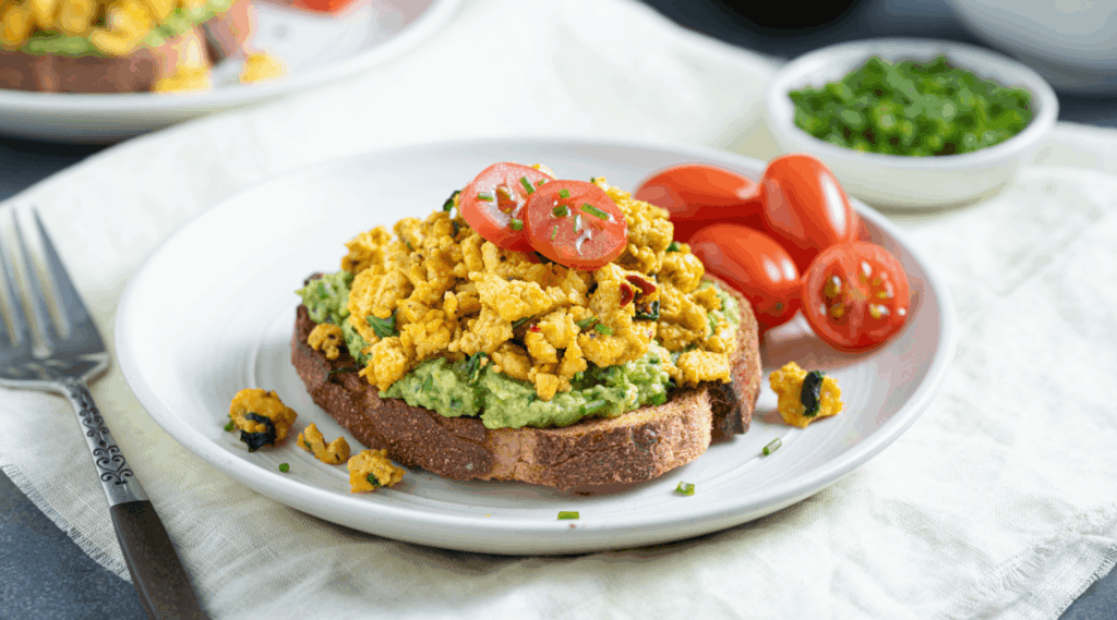 Close up of plate with fork with slice of toast topped with tofu scramble and fresh tomatoes as a healthy recipe for brunch or breakfast