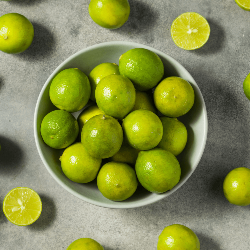 Overhead image of bowl of key limes on grey table