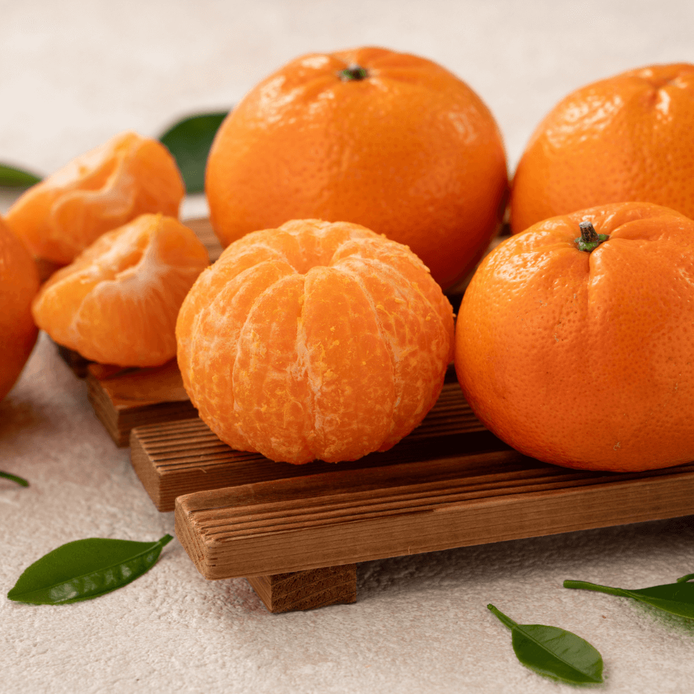 Whole and peeled tangerines on wooden board
