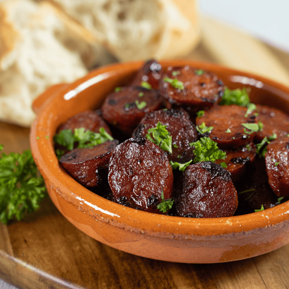 Terracotta dish filled with red wine braised chorizo sausage for Spanish tapas