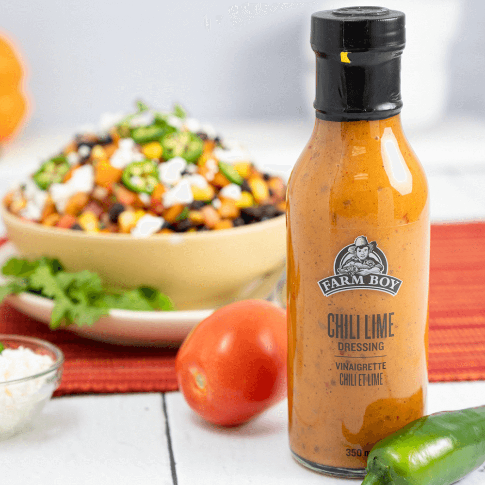 Bottle of Farm Boy Chili Lime Dressing in foreground of salad
