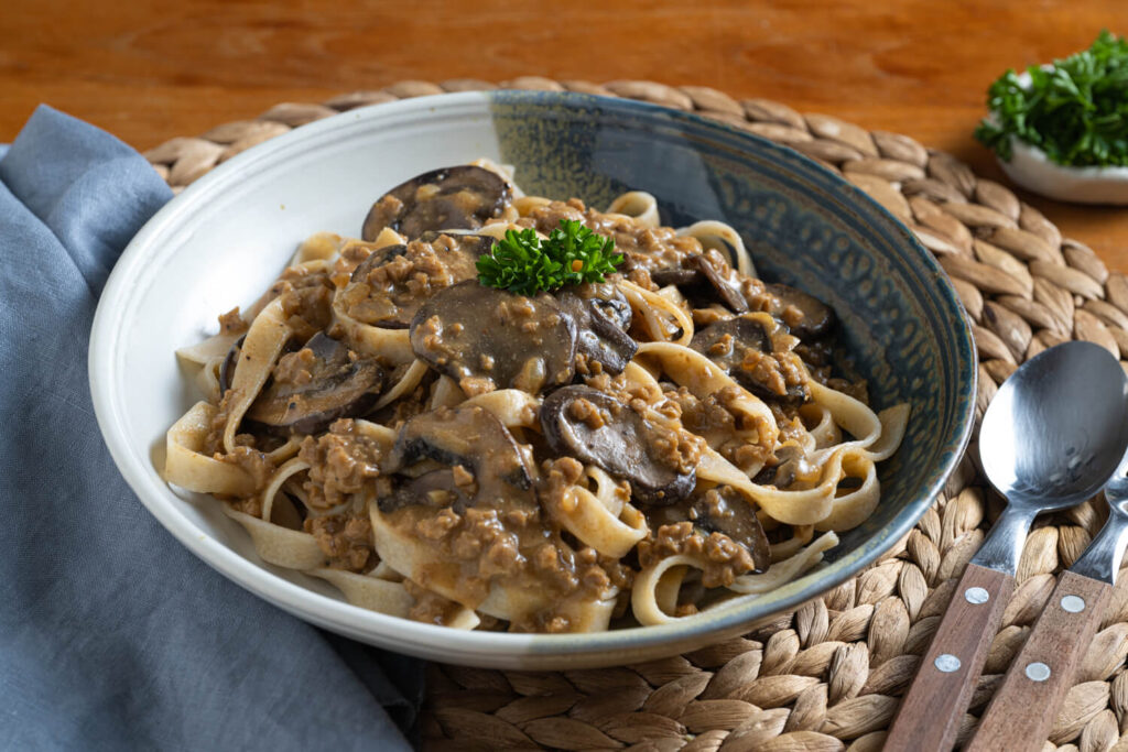 Bowl with plant-based mushroom stroganoff and pasta garnished with fresh parsley for plant-based dinner