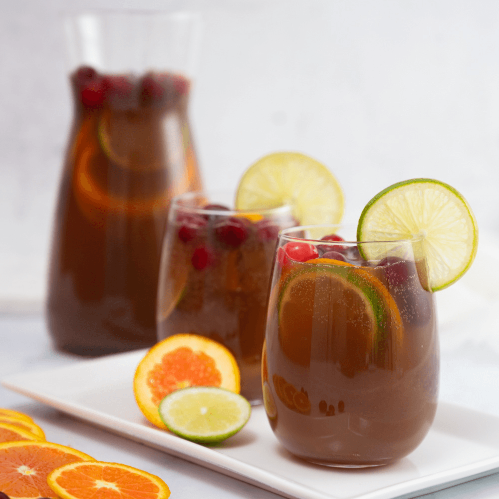 Two glasses of pomegranate fruit punch garnish with citrus wheels and cranberries