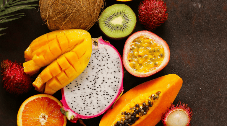 fresh tropical fruits - rambutan, papaya, kiwi, mango, coconut, dragonfruit on a wooden background