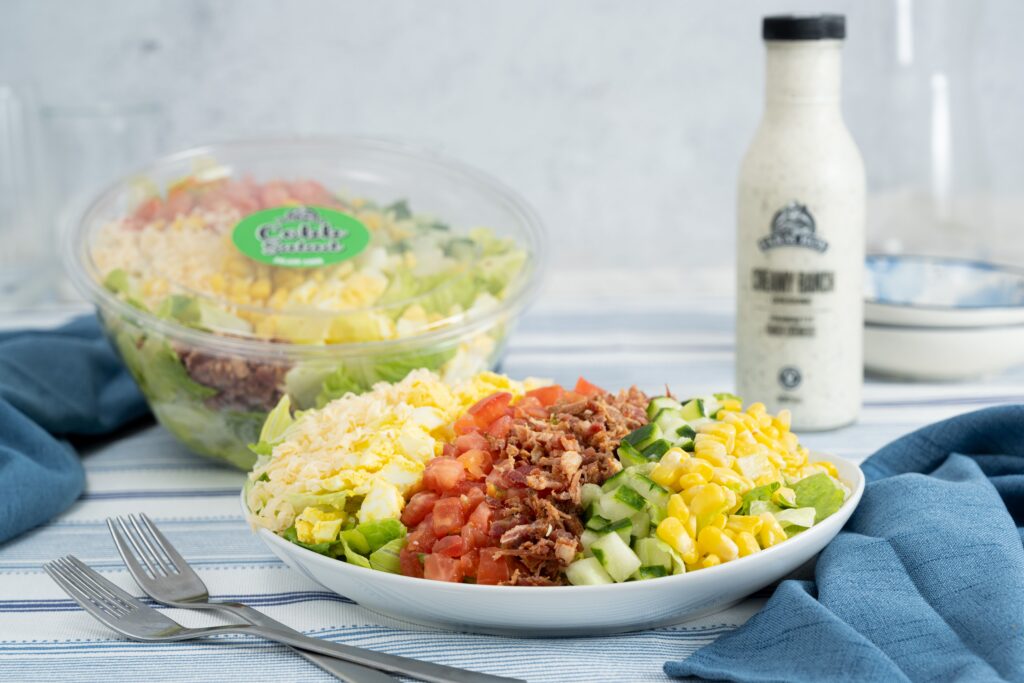 Plate of Farm Boy Cobb Salad with rows of diced tomatoes, egg, corn, and lettuce