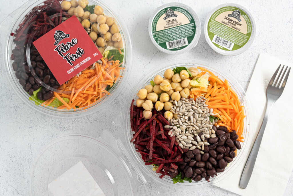 Overhead image of two containers of Farm Boy Fibre First Salad with sunflower seeds, chickpeas, beets, carrots, black beans, and kale