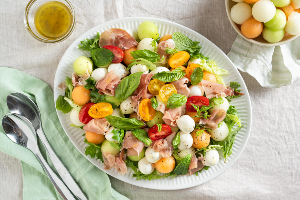 Overhead image of an ultimate salad recipe with fresh balls of melon, mini bocconcini cheese, and cherry tomatoes