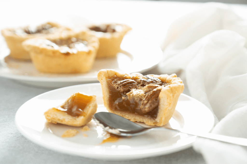Close up of pecan butter tart on plate with filling visible
