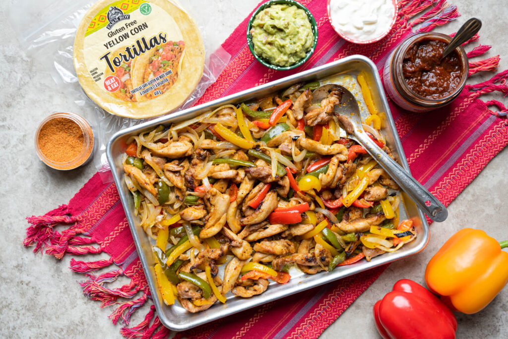 Overhead image of sheet pan chicken fajitas with roasted onions and peppers.