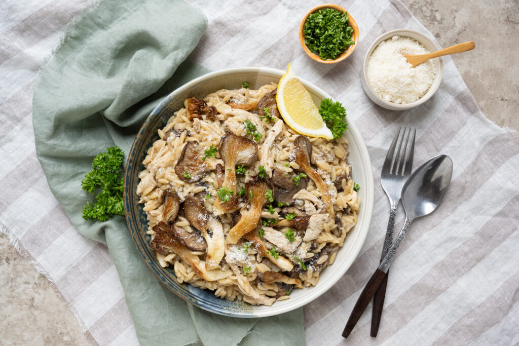 Overhead image of turkey mushroom orzotto garnished with fresh chopped parsley and lemon wedge